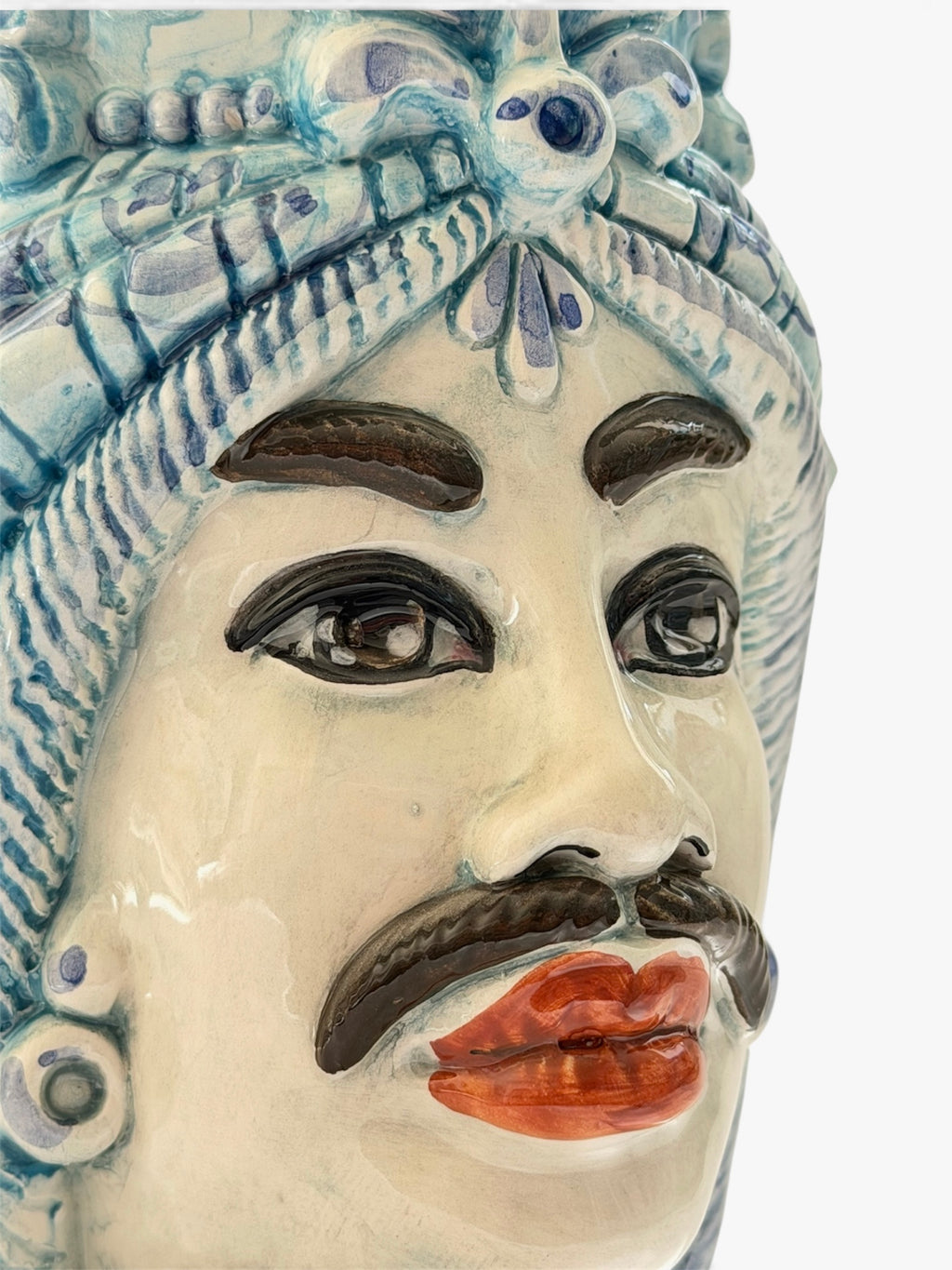 Dettaglio del volto maschile della Testa di Moro Afro, con baffi e decorazioni blu