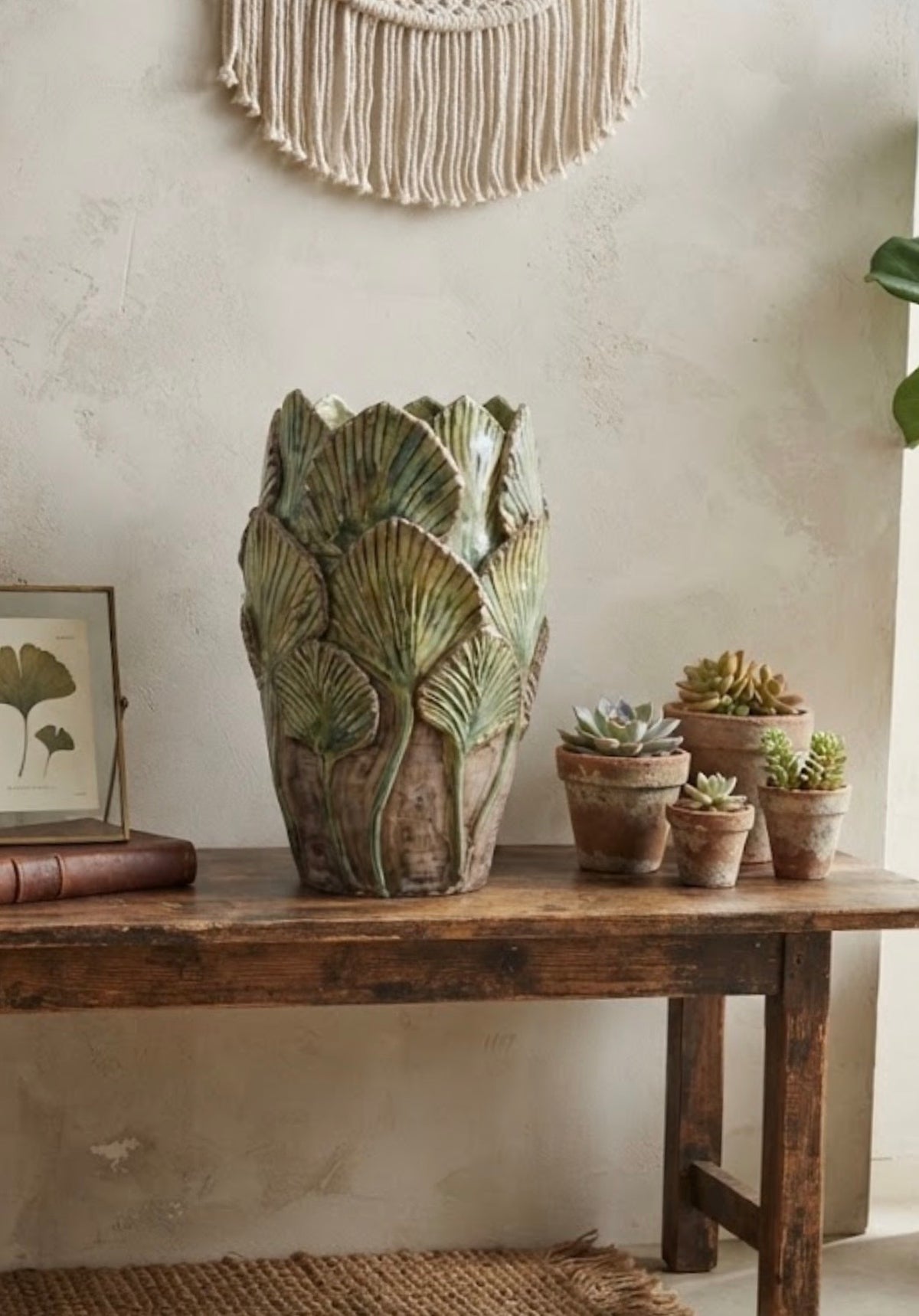 Vaso Bali Collection verde pennellato con foglie in rilievo, ambientato su una consolle in legno