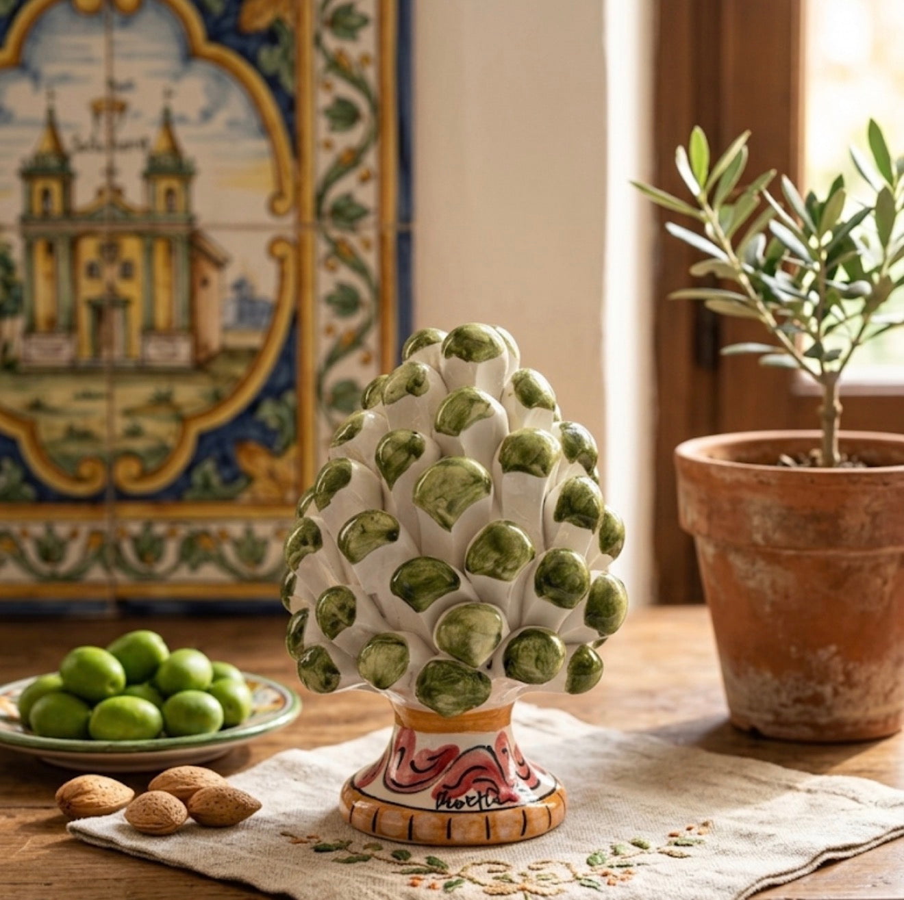 Pigna siciliana verde oliva in ambiente mediterraneo con maioliche e olive