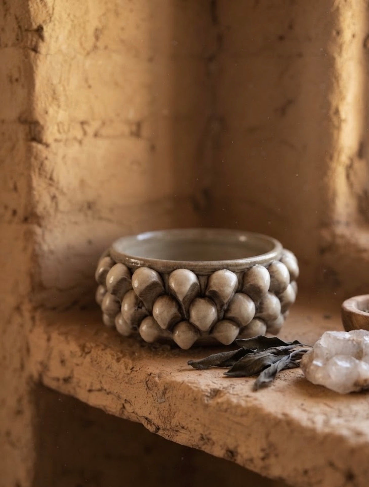 Svuotatasche Pigna in ceramica tortora pennellato, ambientato su una mensola in pietra