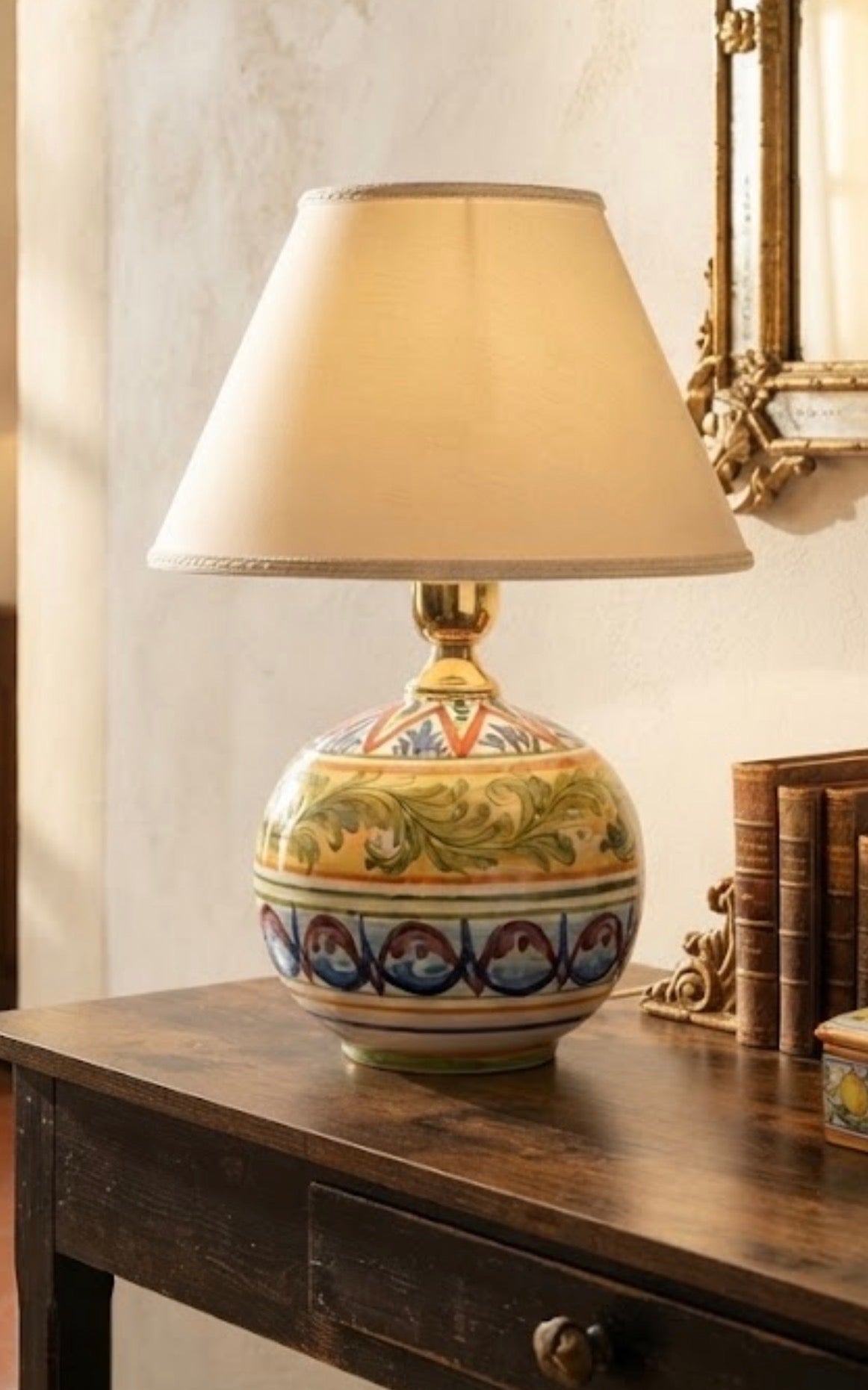 Base per lampada Acanto in ceramica policroma ambientata su un mobile, con paralume dimostrativo non incluso